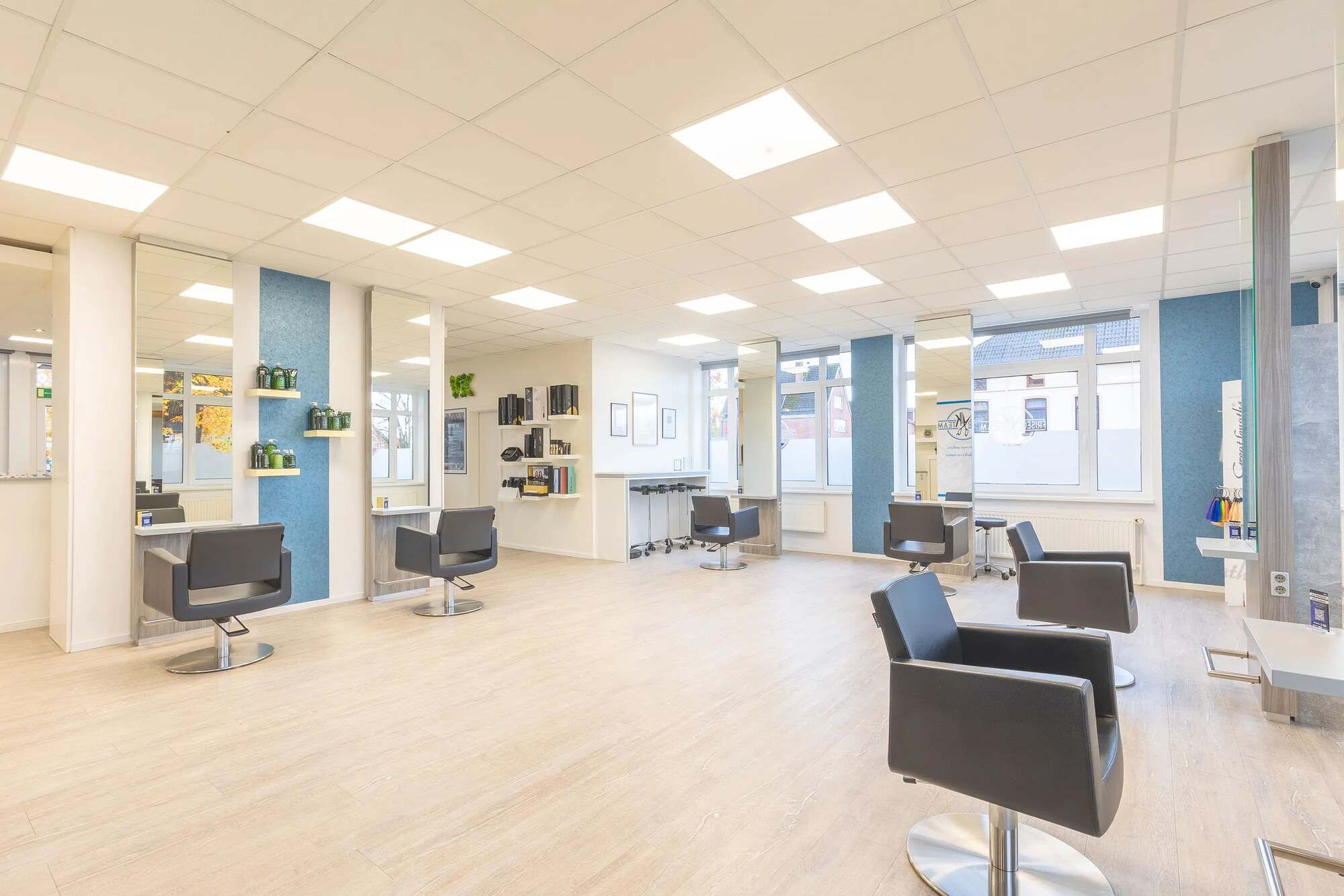 Der helle Salon in der Kastanienallee mit Bedienplätzen und blauen Wandpaneelen